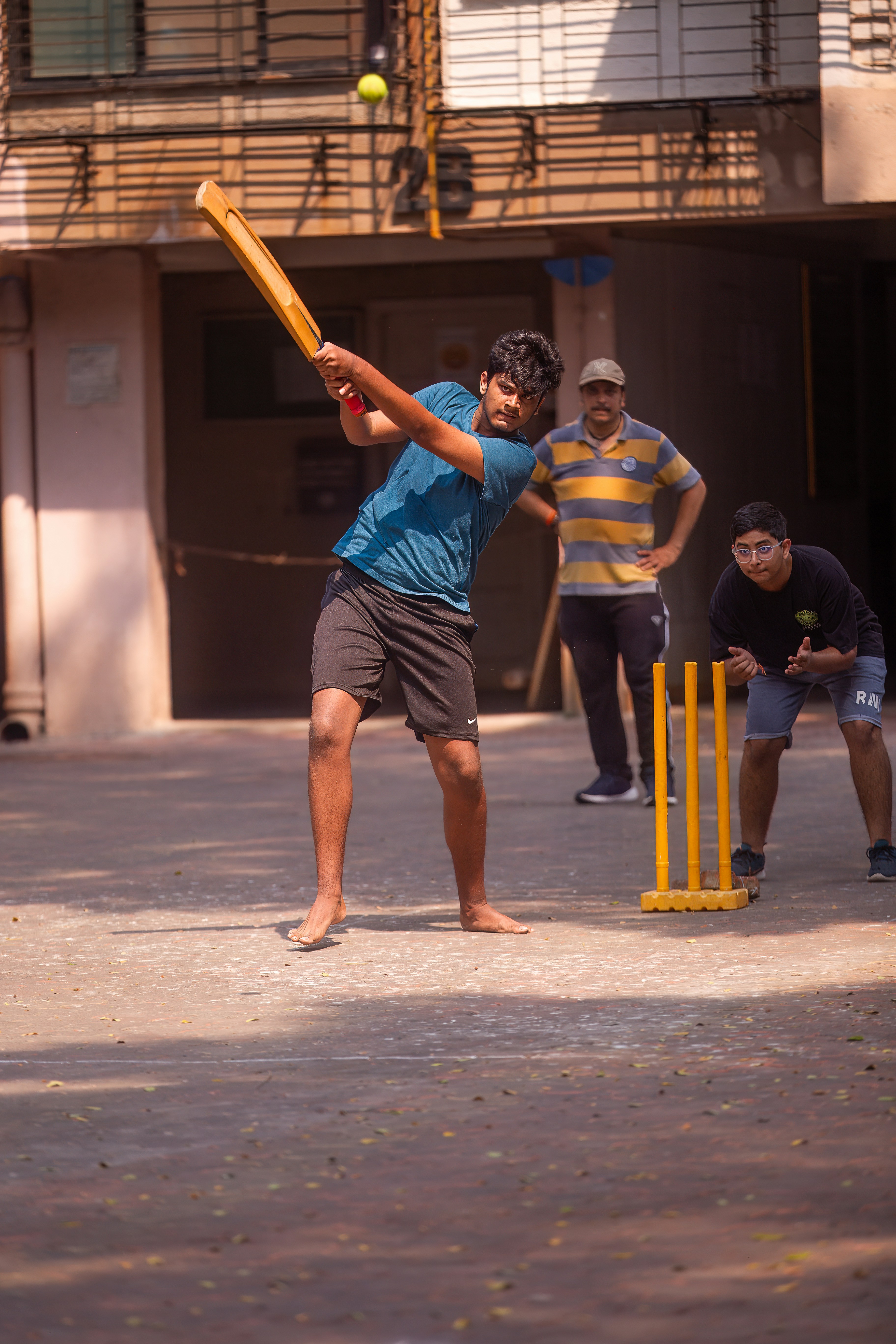 Colony cricket in an apartment courtyard with a wicket-keeper behind plastic stumps
