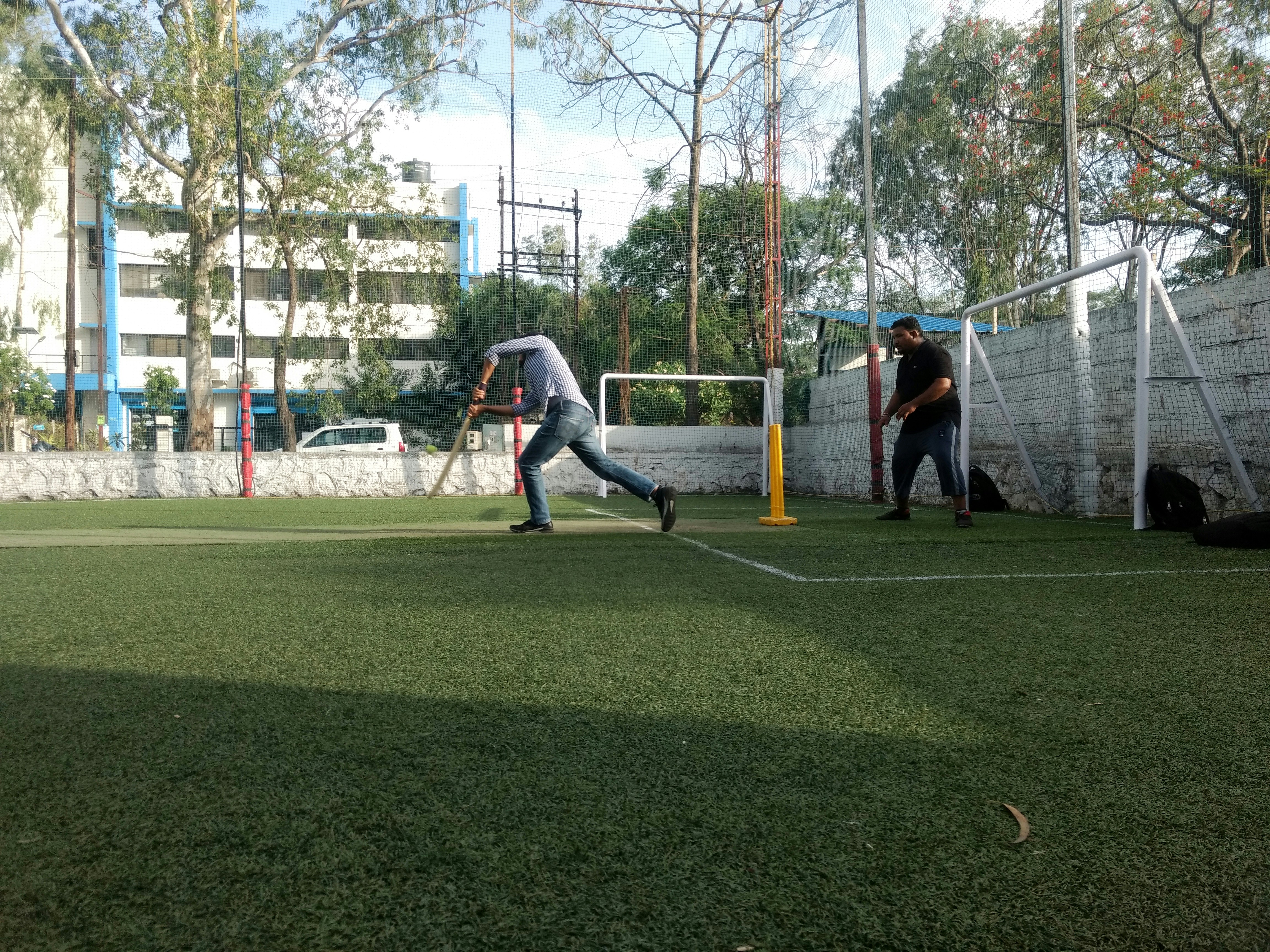 A batter drives on an artificial-turf box-cricket ground